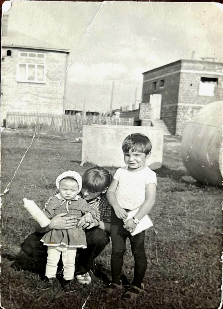 Mama z dwójką dzieci pozuje do zdjęcia przed nowo wybudowanymi domami przy ulicy Lipowej na Osiedlu Słonecznym w Głogowie.