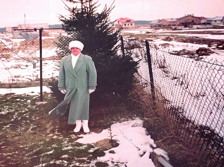 Pani Rusin pozuje do zdjęcia zimą w ogrodzie jednego z domów w Głogowie.