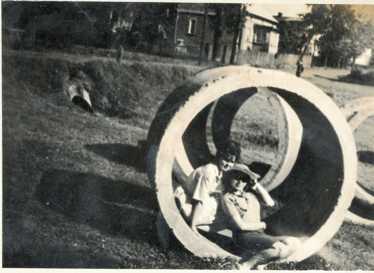 Siostry Irena (po mężu Miazga) i Janina Ozgówny pozują do zdjęcia W betonowym kręgu , leżącym niedaleko Szlachcianki przy ulicy Fabrycznej. W tle dom przy ulicy Fabrycznej nr 2 i przepust na Szlachciance.