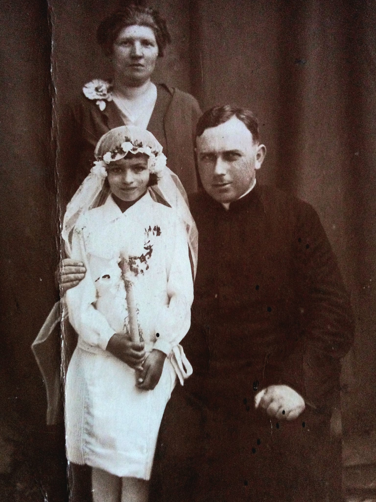 Pani Irena Tomczyk z księdzem Jakubem Forysiewiczem i nauczycielką pozują do pamiatkowego zdjecia z okazji I Komunii Św.