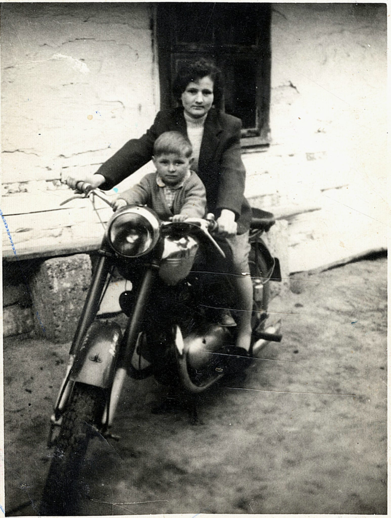 Pani Maria Kaczor wraz z chrześniakiem Ryszardem pozuje do zdjęcia na motocyklu obok domu rodzinnego w Przewrotnem.