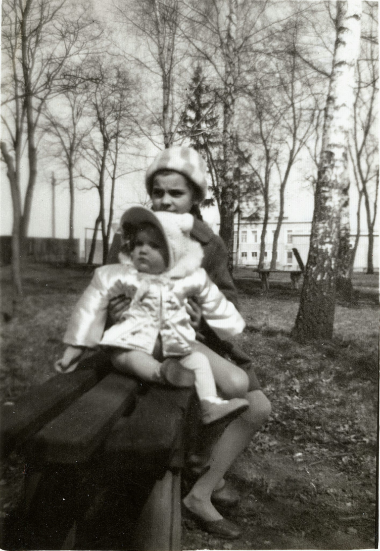 Pani Krystyna Kostrzewska z Marią Tarką na rękach pozuje do zdjęcia na ławce w parku miejskim „Grabina”.