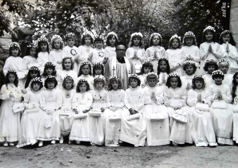 Dzieci z rocznika ’61 pozują do pamiątkowego zdjęcia z ks. Puzio obok kościoła parafialnego w Głogowie.