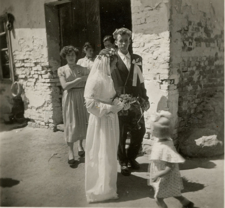 Państwo młodzi Maria i Mieczysław Wszołowie wychodzą ze swojego domu rodzinnego przy ulicy 3-go Maja w Głogowie w otoczeniu gości weselnych.