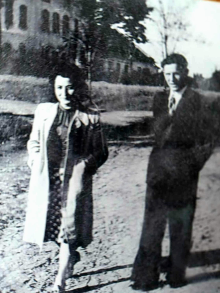 Maria i Stefan Gniewek pozują do zdjęcia na tle fabryki „Lnianka”.