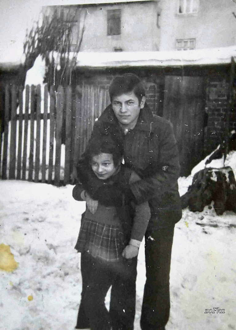 Pani Zofia Łagowska ze swoim starszym bratem Jerzym pozuje do zdjęcia na tle tzw. komórek gospodarczych , które należały do mieszkańców ul. 11-go Listopada (ówcześnie Tkaczowa) i Krzywej. W tle widoczna kamienica nr 3 przy ulicy Krzywej.