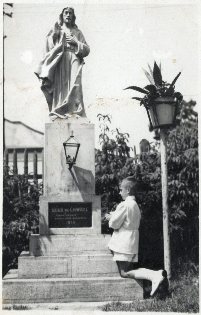 Młody chłopiec modli się po uroczystości I Komunii Św. przed kapliczką z figurą Chrystusa , którą w 1945 r. ufundował p. Andrzej Brzuza.