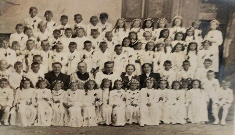 Pamiątkowe zdjęcie z okazji I Komunii Św. w Głogowie. Dzieci pozują do zdjęcia wraz z p.Czech , p. Manelską , Ks.Forysiewiczem i Ks. Musiałem.