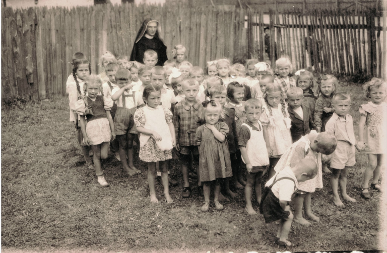 Dzieci wraz z zakonnicą przed budynkiem ochronki w Głogowie.