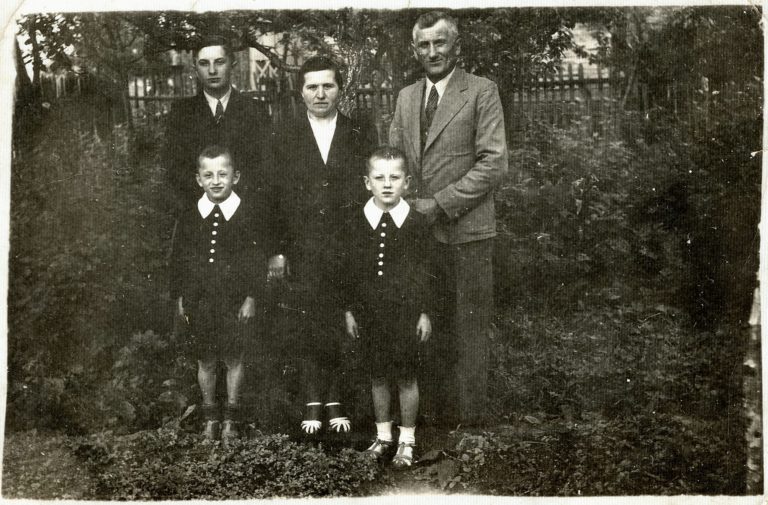 Rodzina Sokołowskich – Maria i Józef z synami Edmundem , Czesławem i Henrykiem , pozują do zdjęcia przed drewnianym domem na ulicy Mickiewicza w Głogowie.