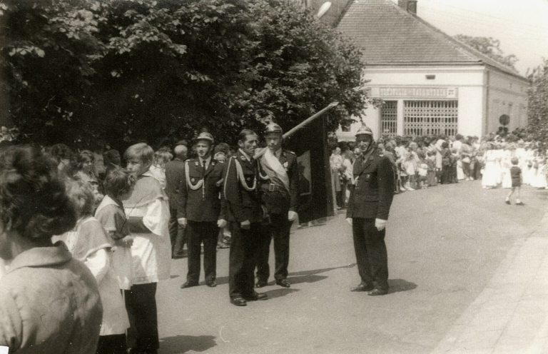 Poczet sztandarowy głogowskiej OSP podczas procesji Bożego Ciała na Rynku w Głogowie.W tle dobrze widoczny sklep galanteryjny pod adresem Rynek nr 24.