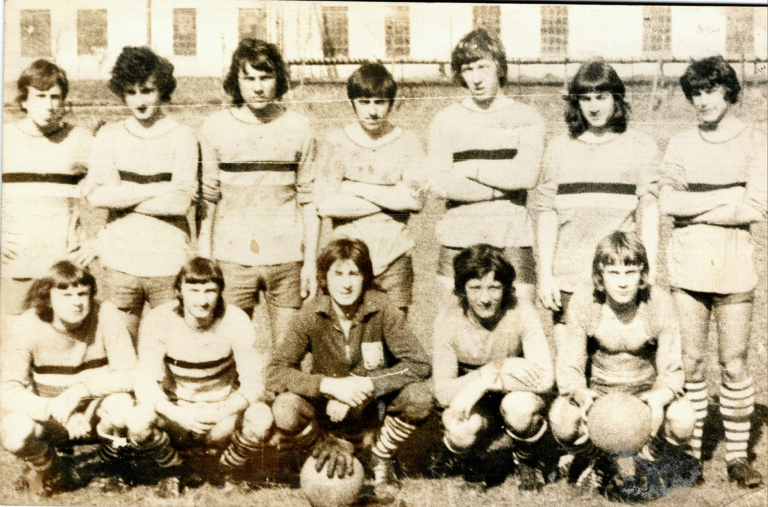 Piłkarze „Głogovii” pozują do pamiątkowego zdjęcia na boisku sportowym w Głogowie.W tle budynek fabryki „Technitex”.