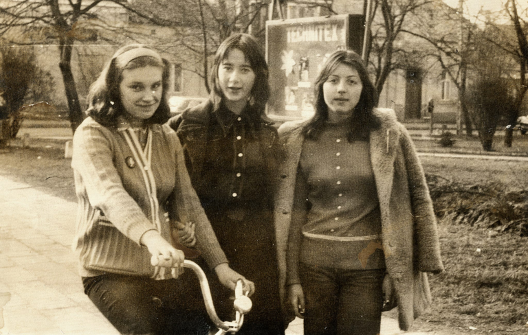 Pani Anna Wszoła (w środku) wraz z koleżankami pozuje do zdjęcia na głogowskich plantach. W tle widoczna tablica z napisem „Technitex” oraz domy w Rynku nr 3 , 4 , 5 i 6.