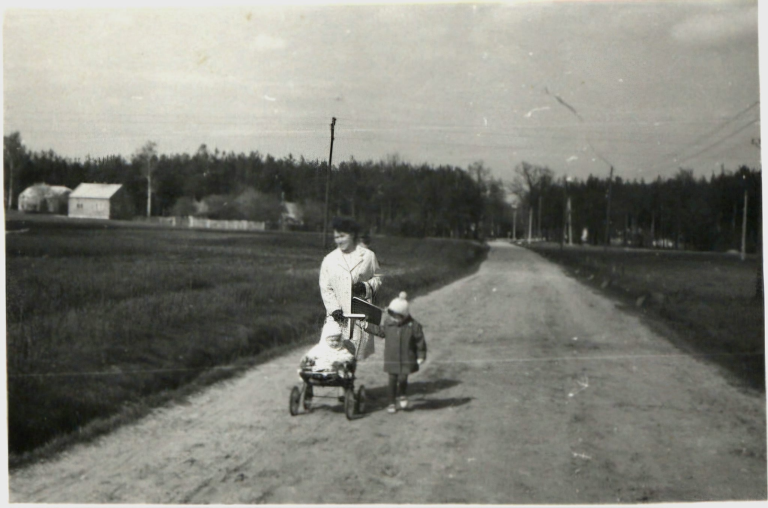 Kobieta z dwójką dzieci idzie ulicą od Piasków w stronę Zabajki. W tle zabudowania na Piaskach.