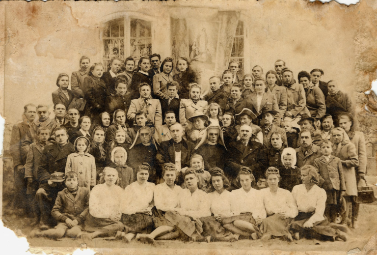 Pamiątkowe zdjęcie zrobione po procesji Bożego Ciała w Głogowie na tle kościoła parafialnego. Na zdjęciu m.in. ks. Forysiewicz.