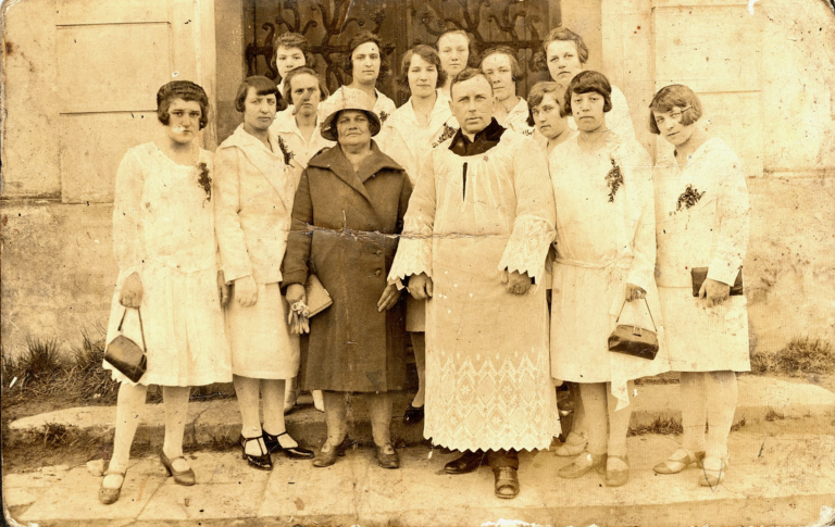 Ks. Forysiewicz z grupą pań (m.in p. Julia Domańska) pozuje do zdjęcia przed wejściem do kościoła parafialnego w Głogowie.