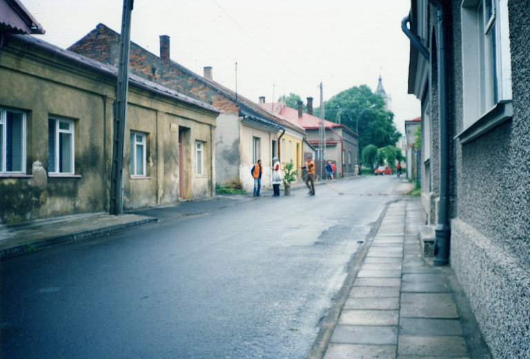 Trzech panów robi „bramę weselną” na ulicy 3-go Maja w Głogowie. W tle widoczne budynki , od lewej : 3-go Maja nr 6 , nr 4 (nieistniejący dzisiaj) i nr 2 , następnie narożny budynek Rynek nr 2 , wieża ratusza , narożny budynek Rynek nr 61 i 3-go Maja nr 1.