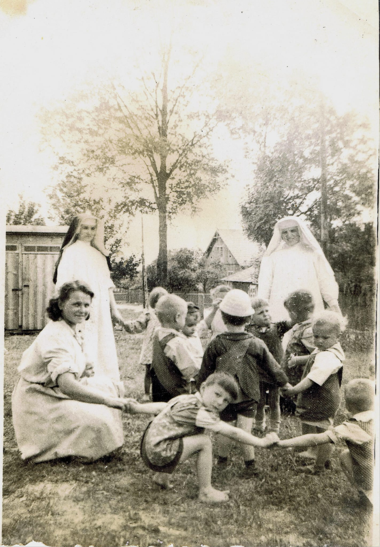 Grupa dzieci , pod opieką zakonnic , bawi się obok budynku ochronki w Głogowie. Jednym z dzieci jest śp. p. Ryszard Porada.